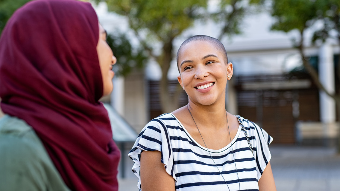 two women speak while outside