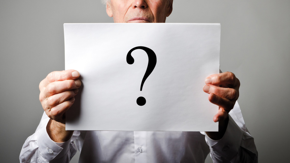 a man holds a sheet of paper with a question mark printed on it