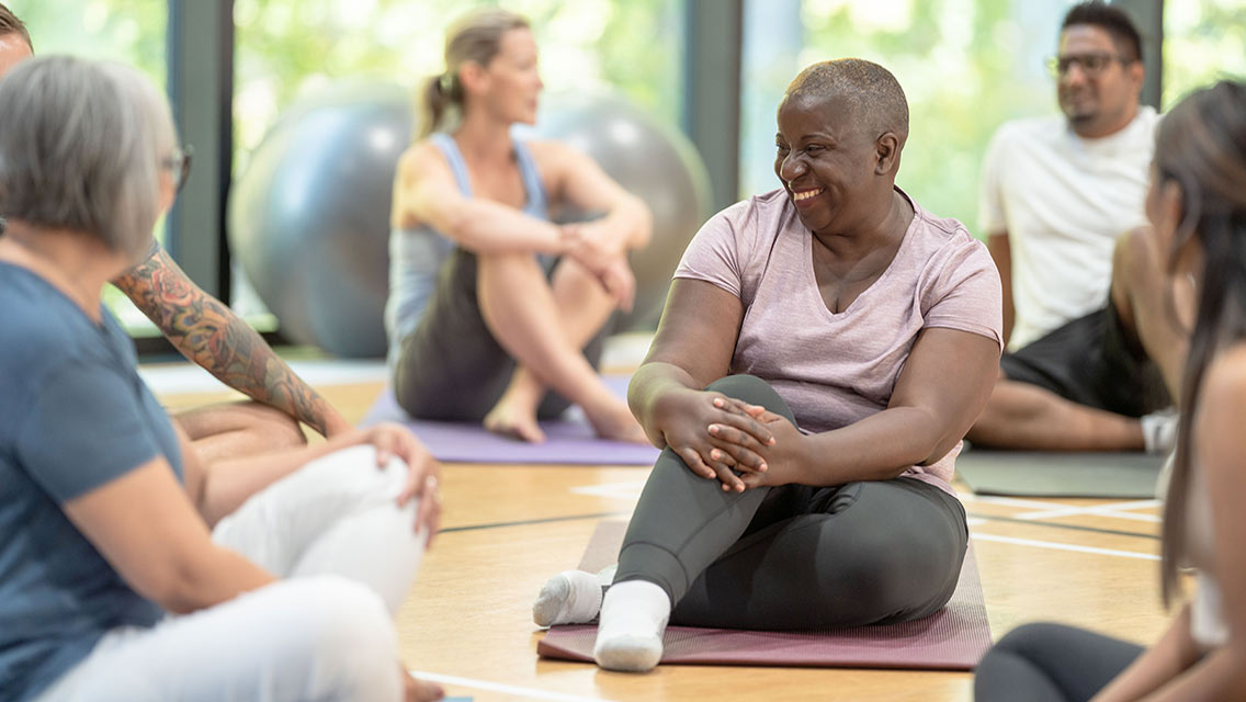 a woman talks with fellow yoga students before class