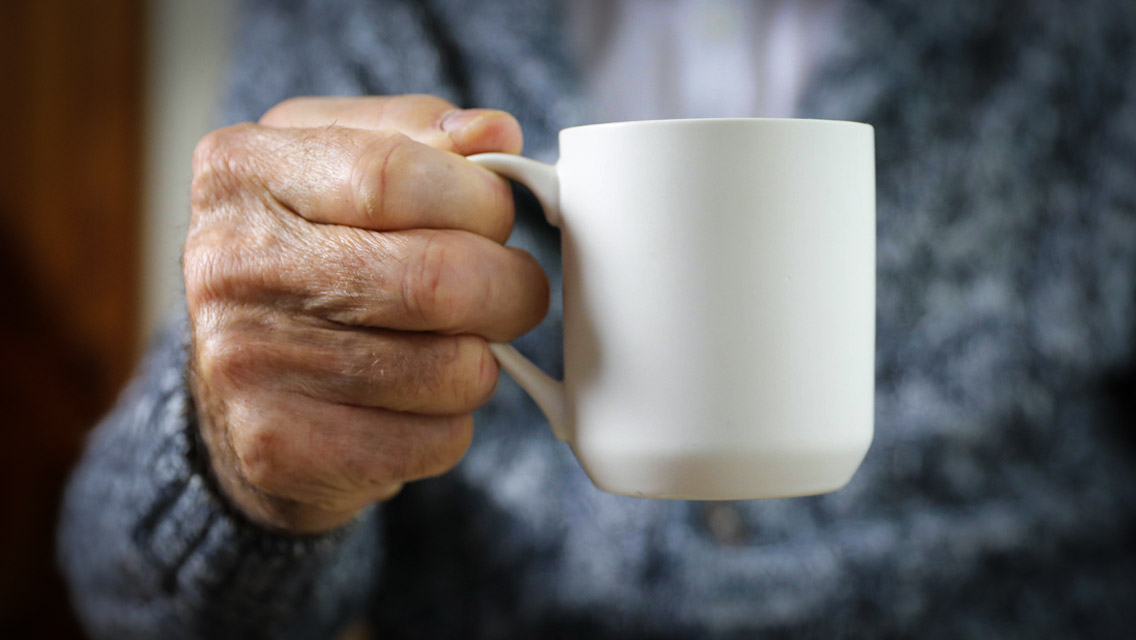 a senior man holding a mug of coffee