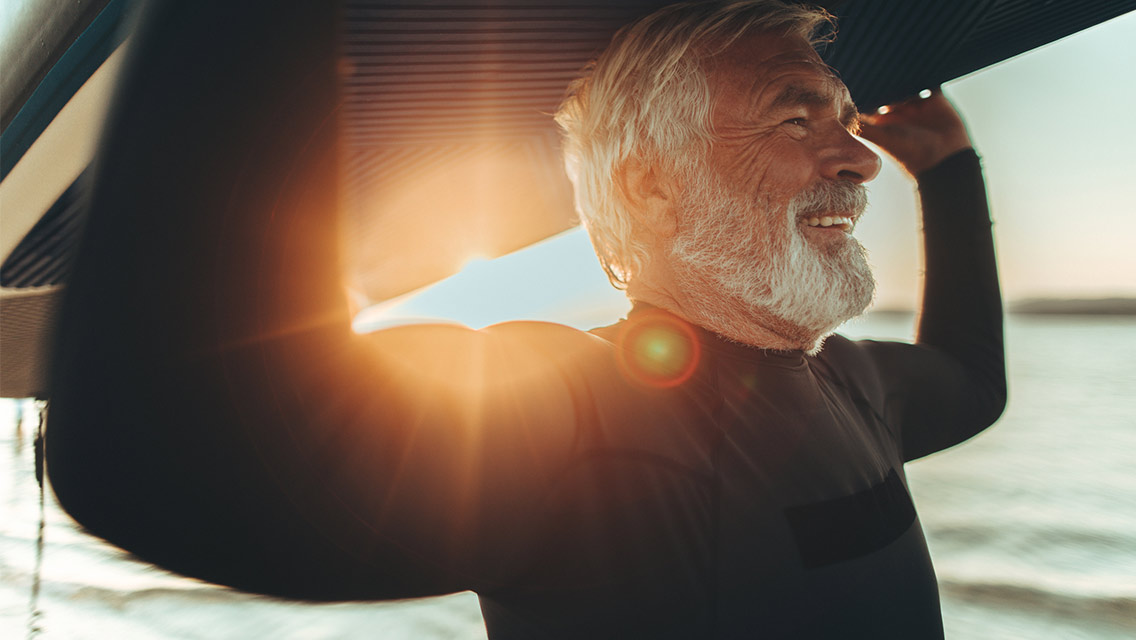 Senior man enjoying surfing at sunset