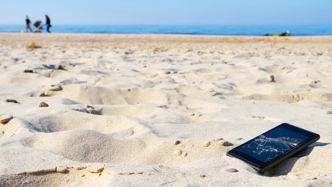 A broken cellphone sits on the beach.