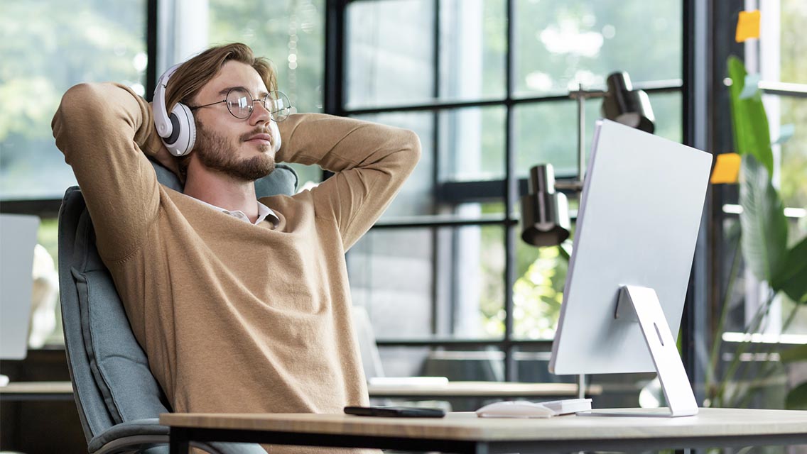 a man sits at his desk with headphones
