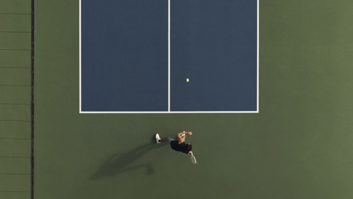 half of a pickleball court and someone playing on one side