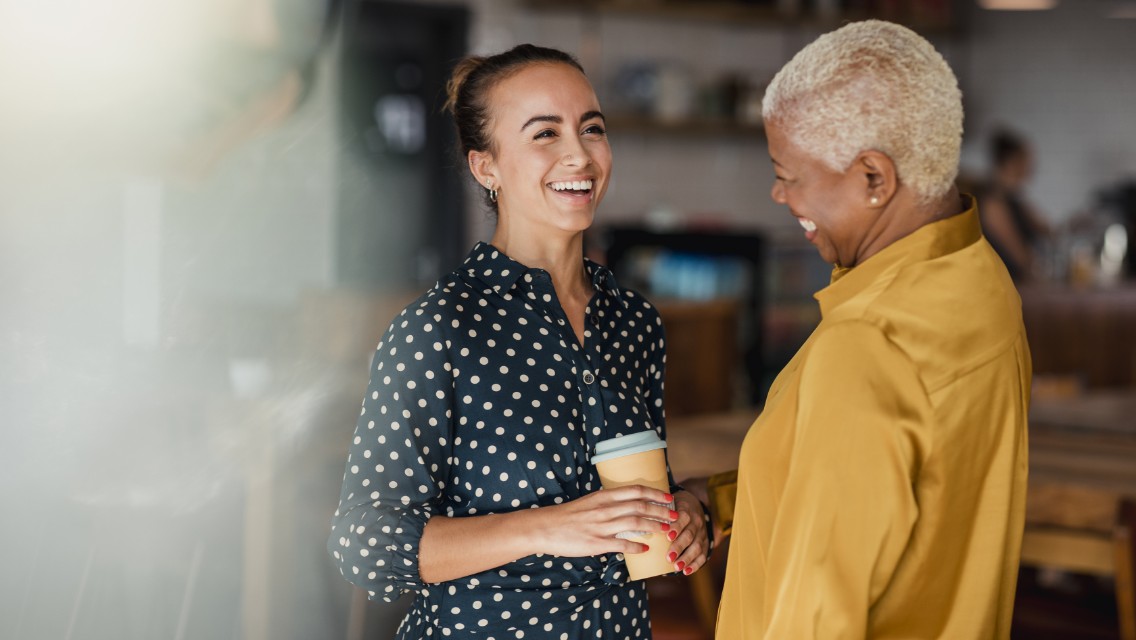 Two women chatting in a workplace setting.