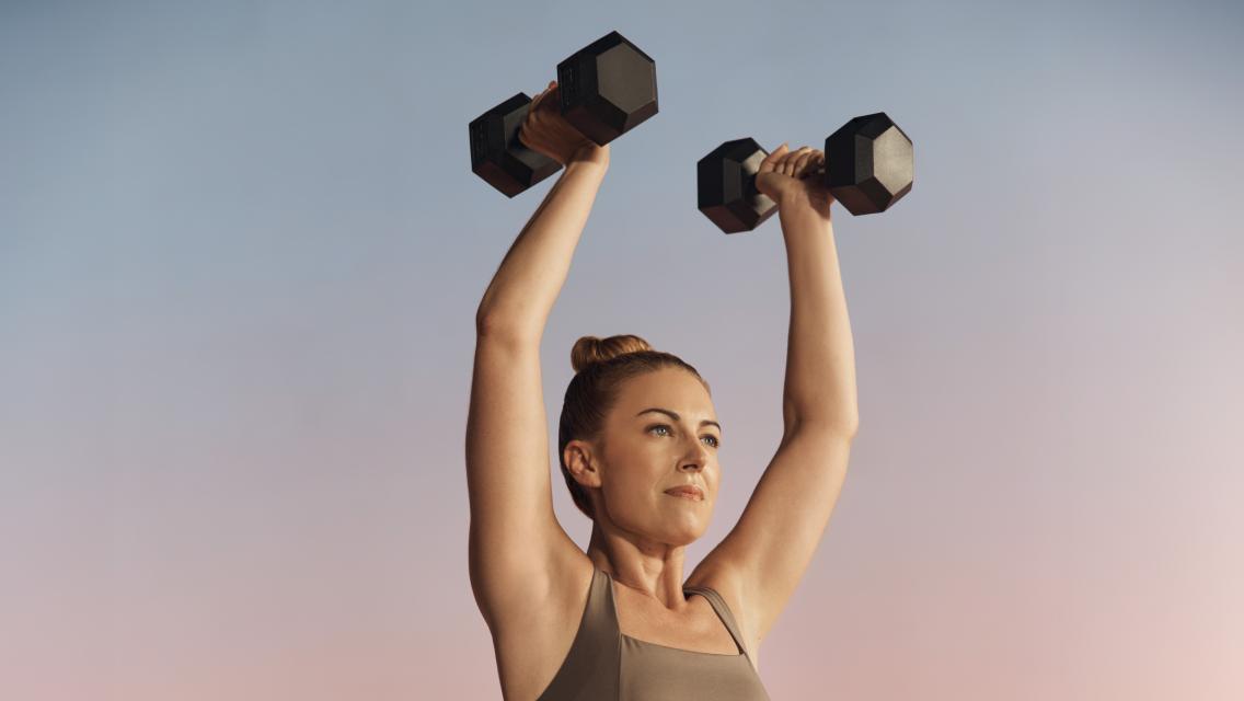 woman with dumbbells over her head