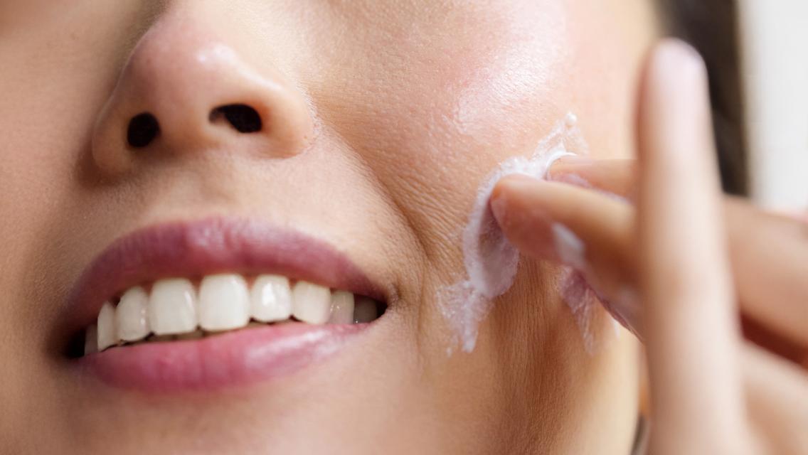 woman putting lotion on face
