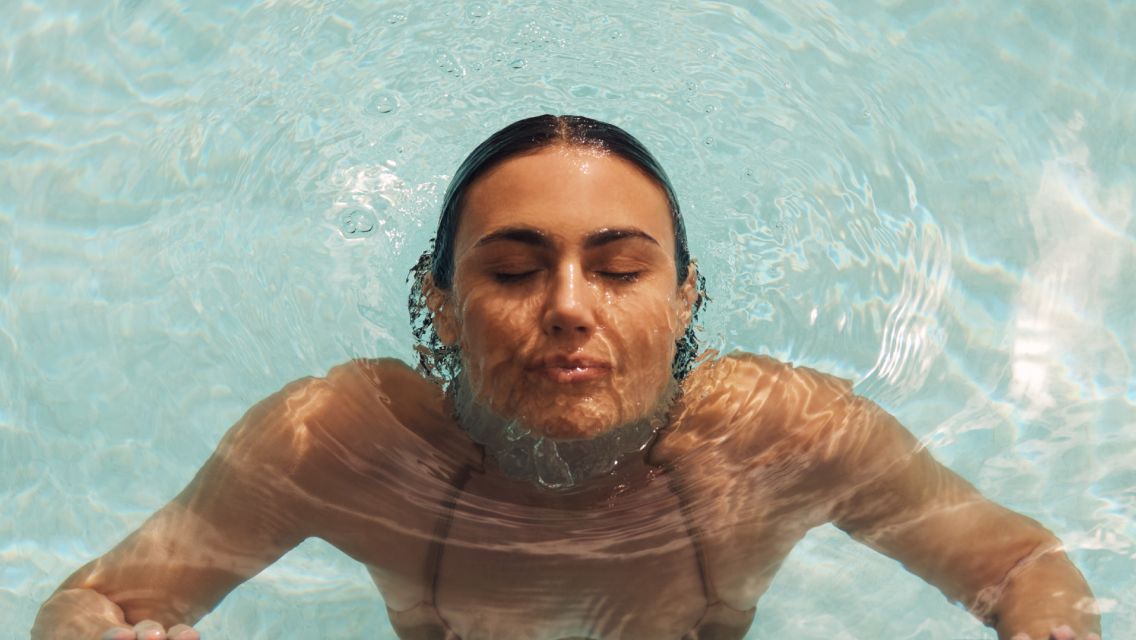 A woman emerging from swimming in a pool.