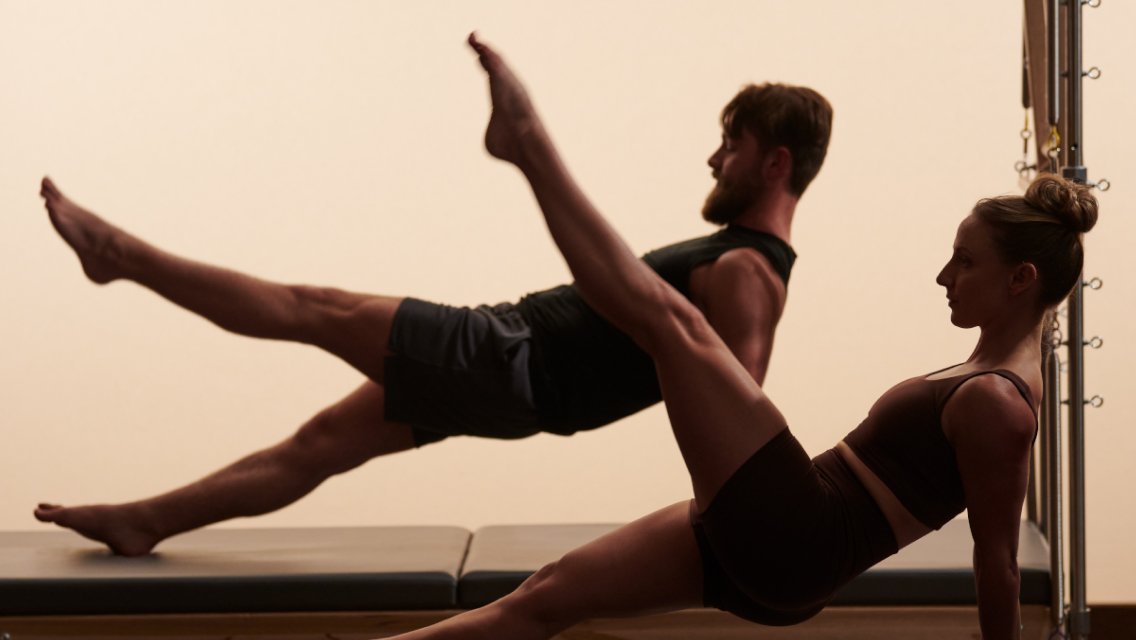 two people on pilates reformer