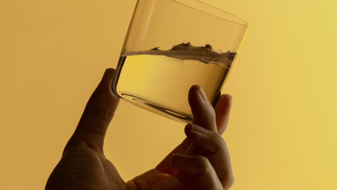 person holding glass of water with supplement in it
