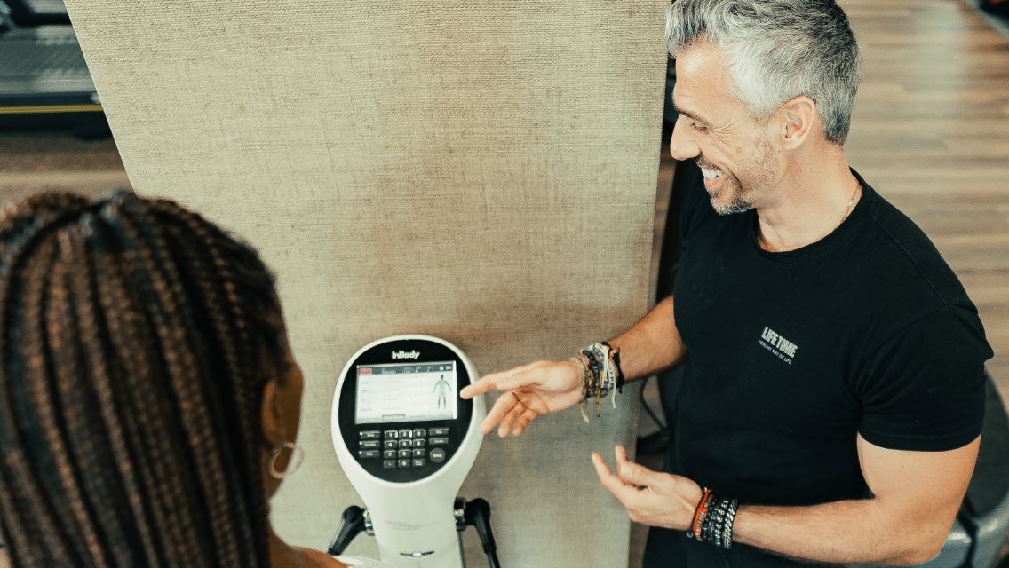 A Life Time team member working with a member who's using the InBody scale in the club.