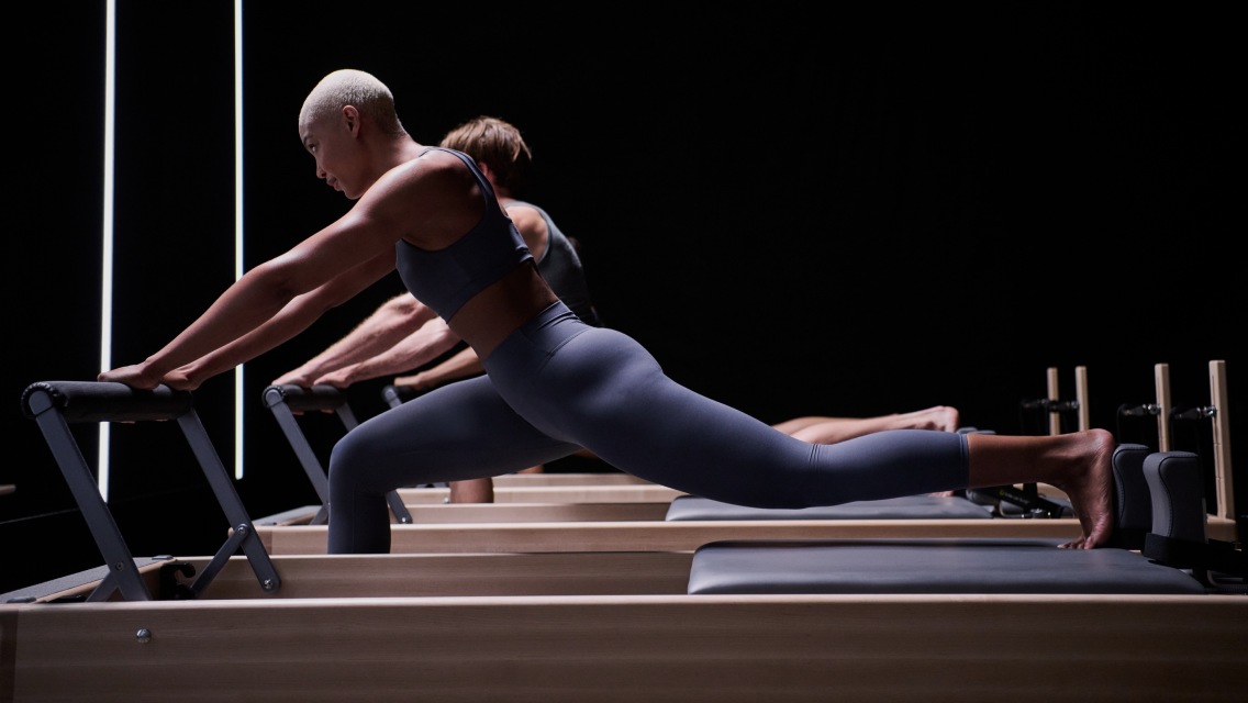 Person doing a lunge move on a Pilates reformer in a CTR class at Life Time