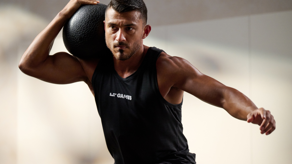 man holding medicine ball on shoulder