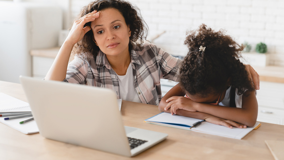 a mom helps her daughter with homework looking overwhelmed