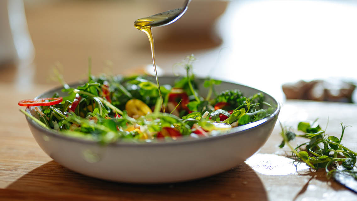 a salad with olive oil being drizzled on it