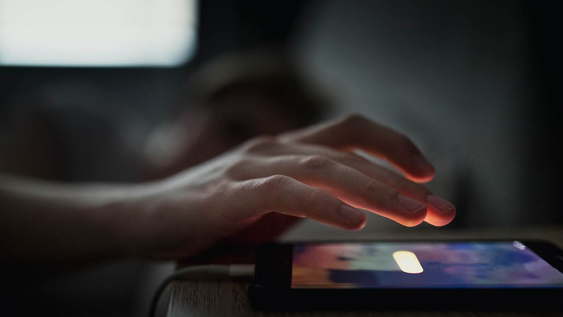 a person works on their computer and phone at night