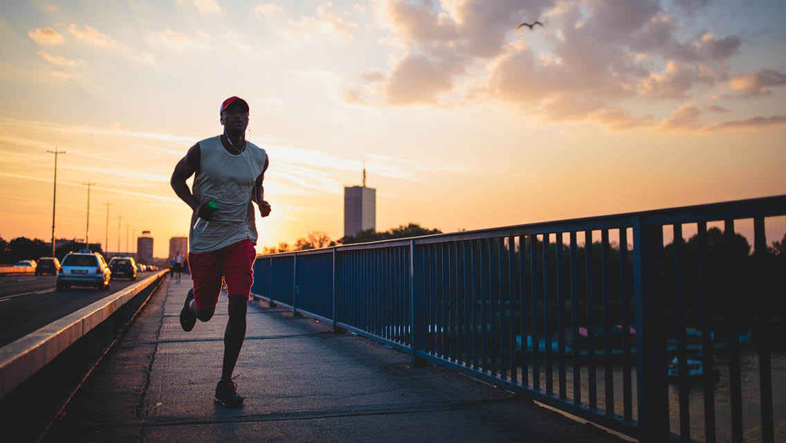 a man runs outside at sunset