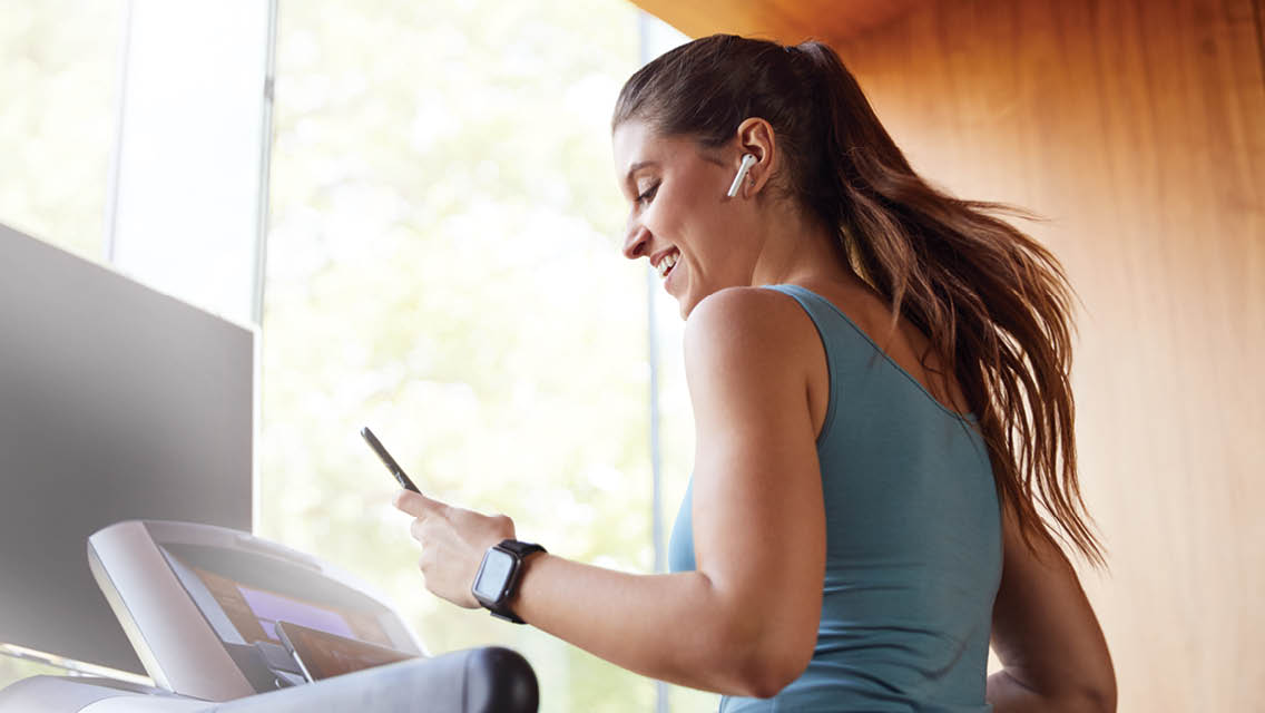 a woman running a treadmill with air pods