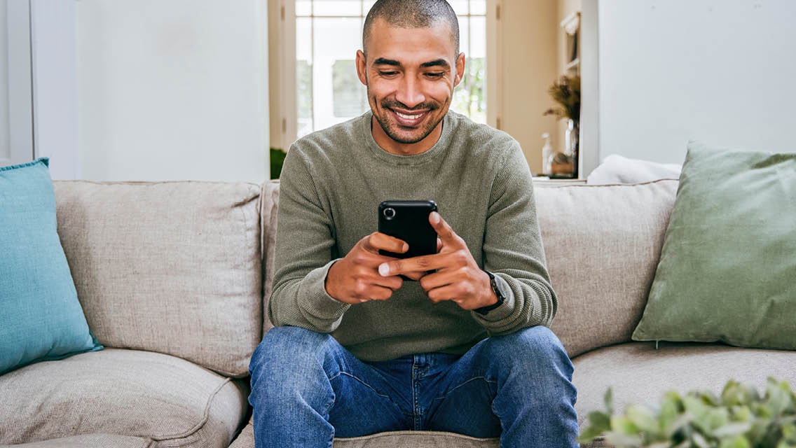 a man smiles while engaging with his phone.