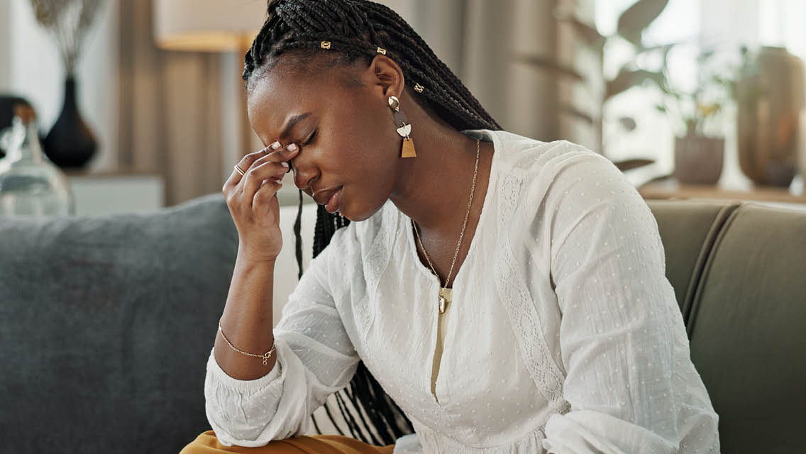 a woman sits on a couch looking depressed and tired