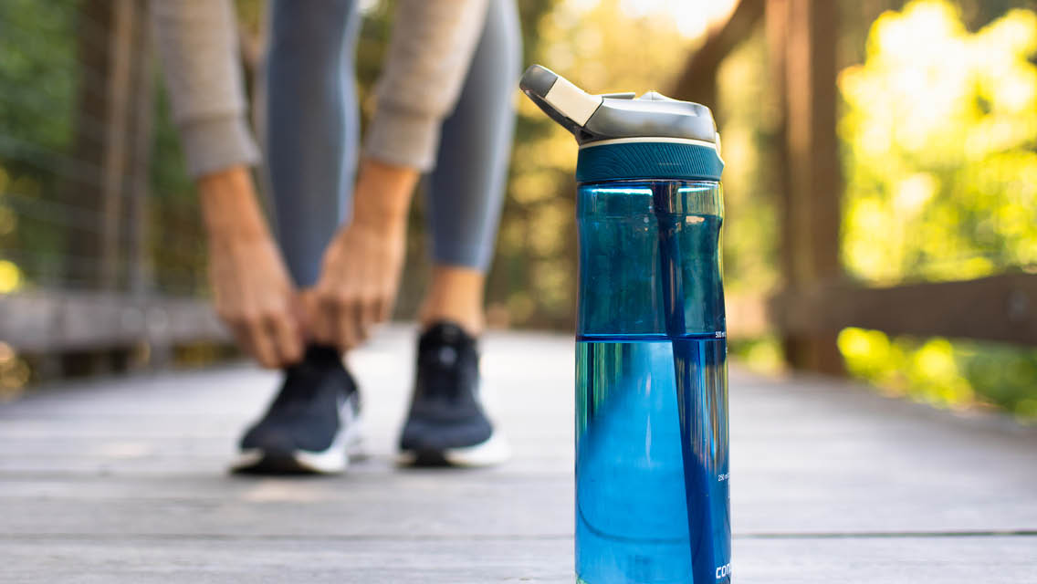 a woman ties her shoes with a water bottle in front of her.