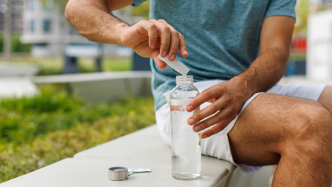 a person pours a packet of electrolytes into a water bottle