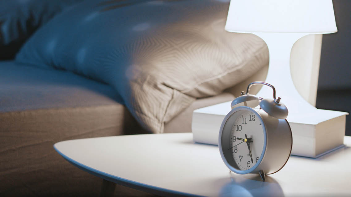 an old fashioned alarm clock sits next to a bed