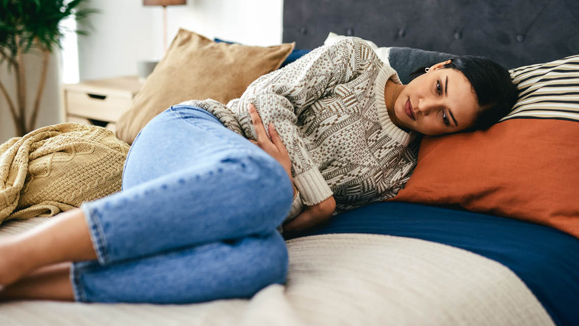 a woman lies in the fetal position with her arms wrapped around her belly