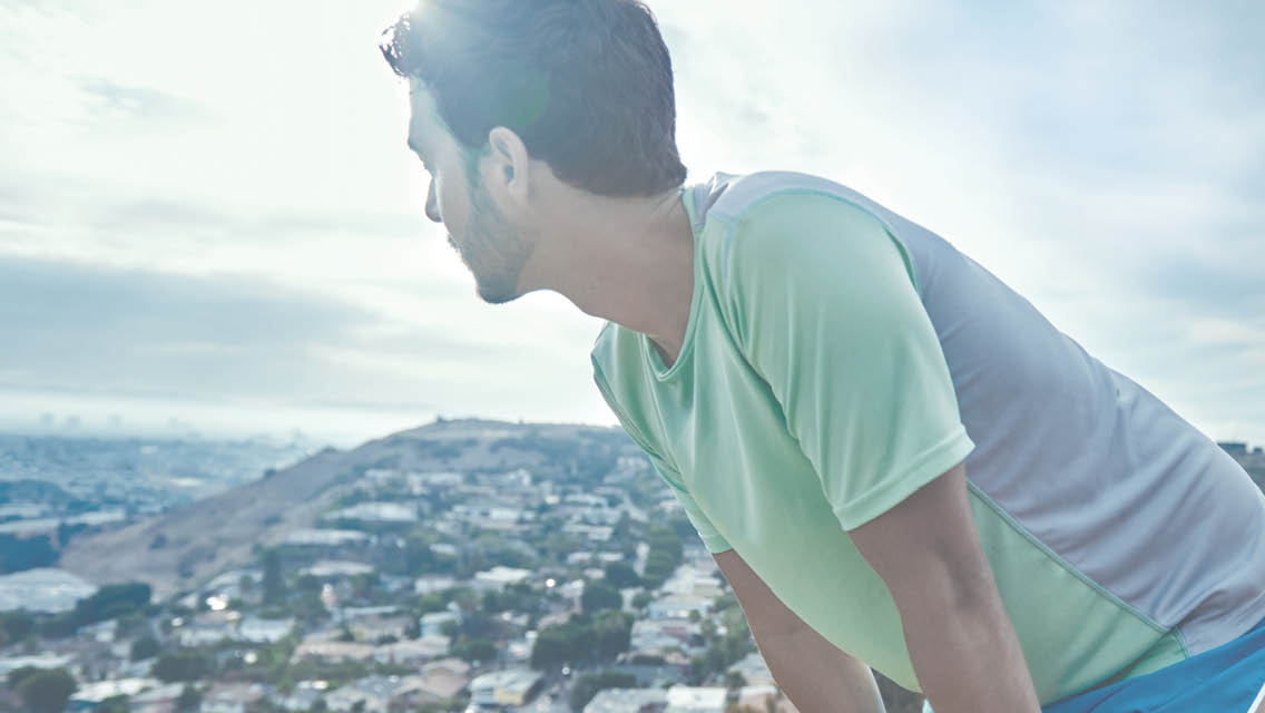 a man stands leaning over looking over a town below him