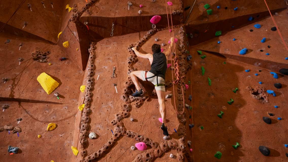 man rock climbing on indoor wall