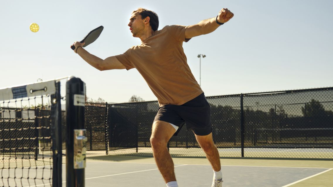 man hitting a pickleball over the net