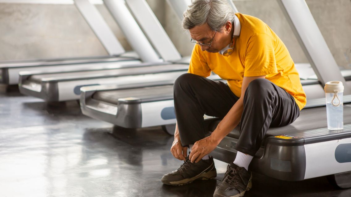 Person sitting on a treadmill tying their shoe