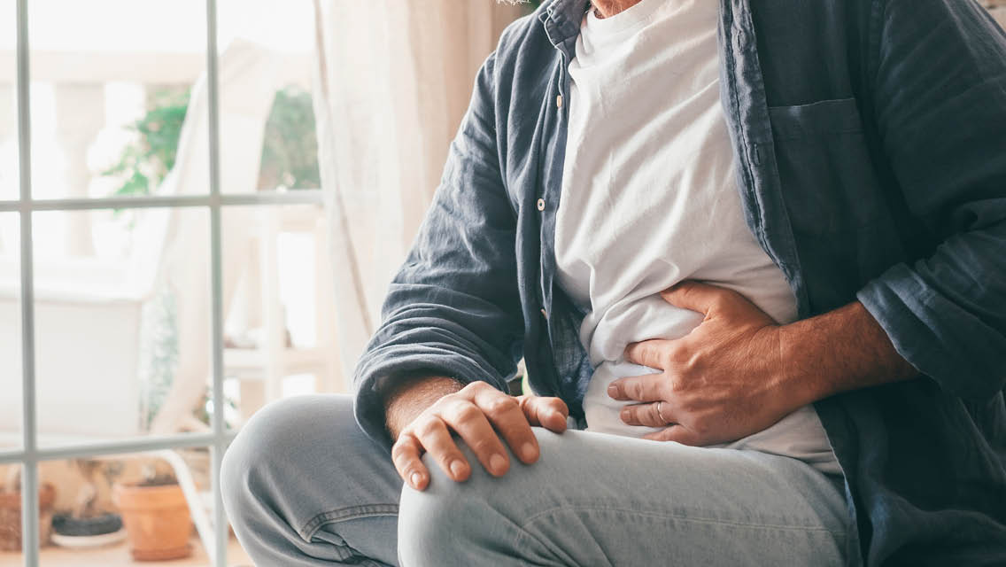 a man places his hand on his uncomfortable stomach