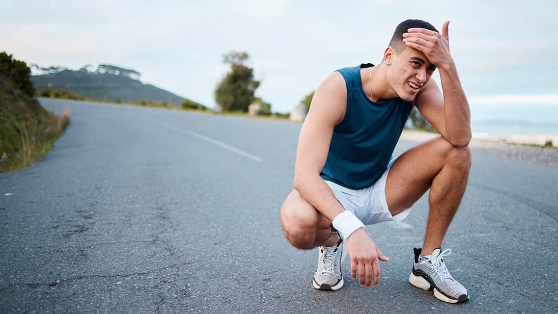 a man squats with his hand on his head