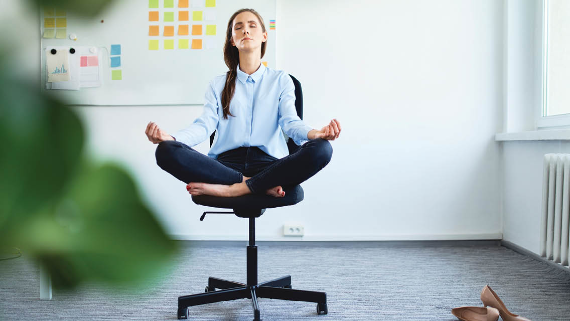 a woman sits cross legged in an office chair