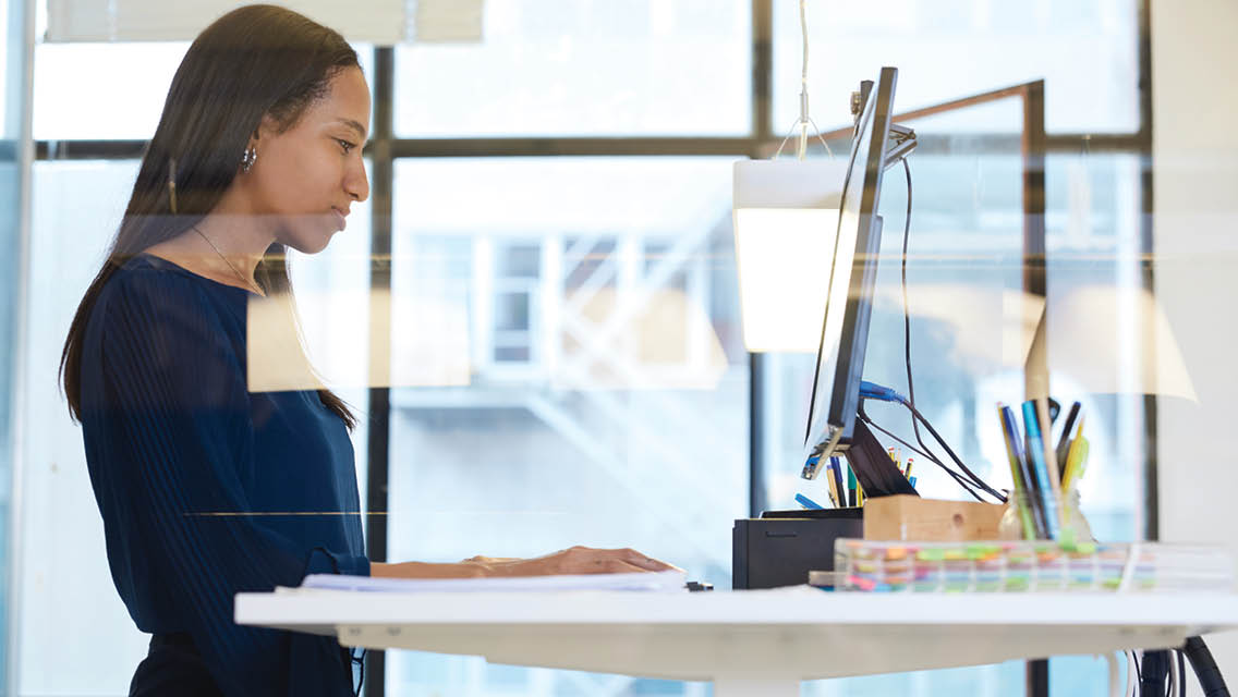 a woman works at a standing workstation