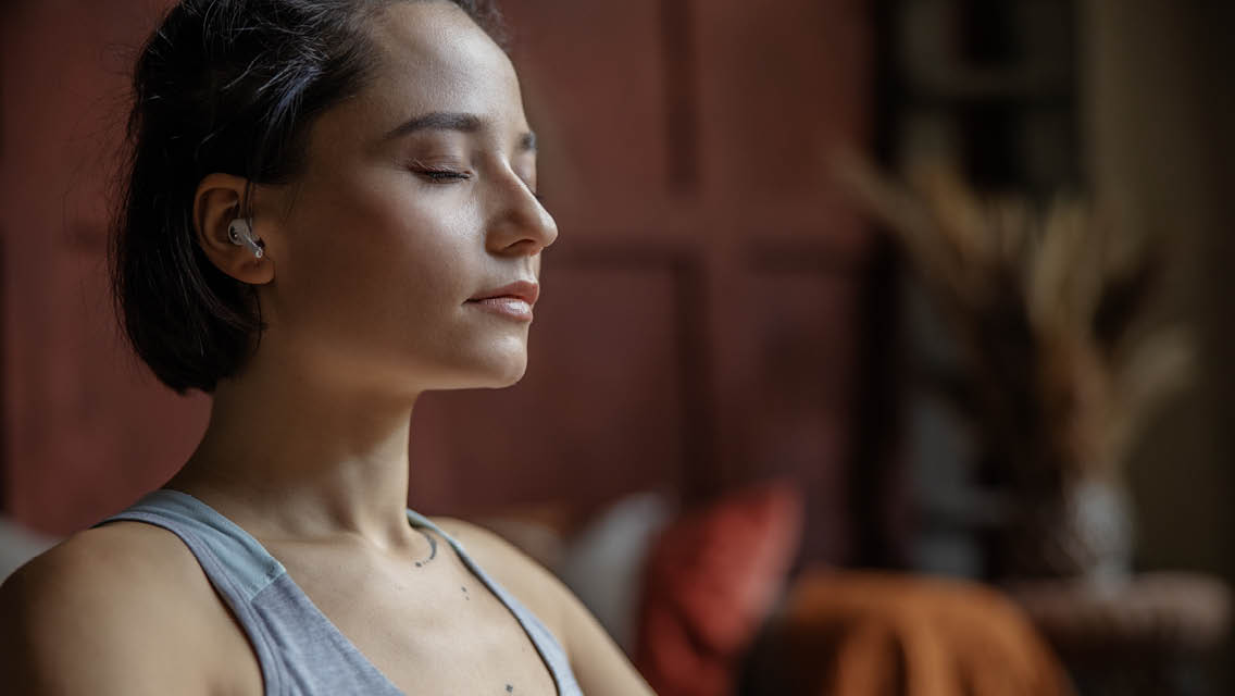 a woman meditates with earphones.