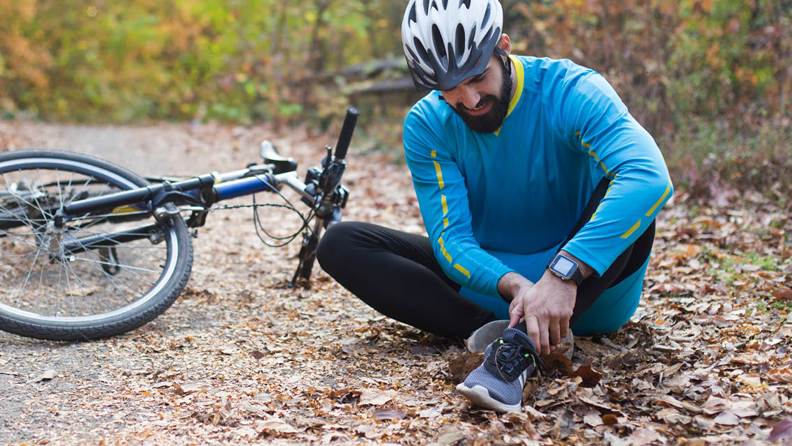 a man holds his ankle after a fall.