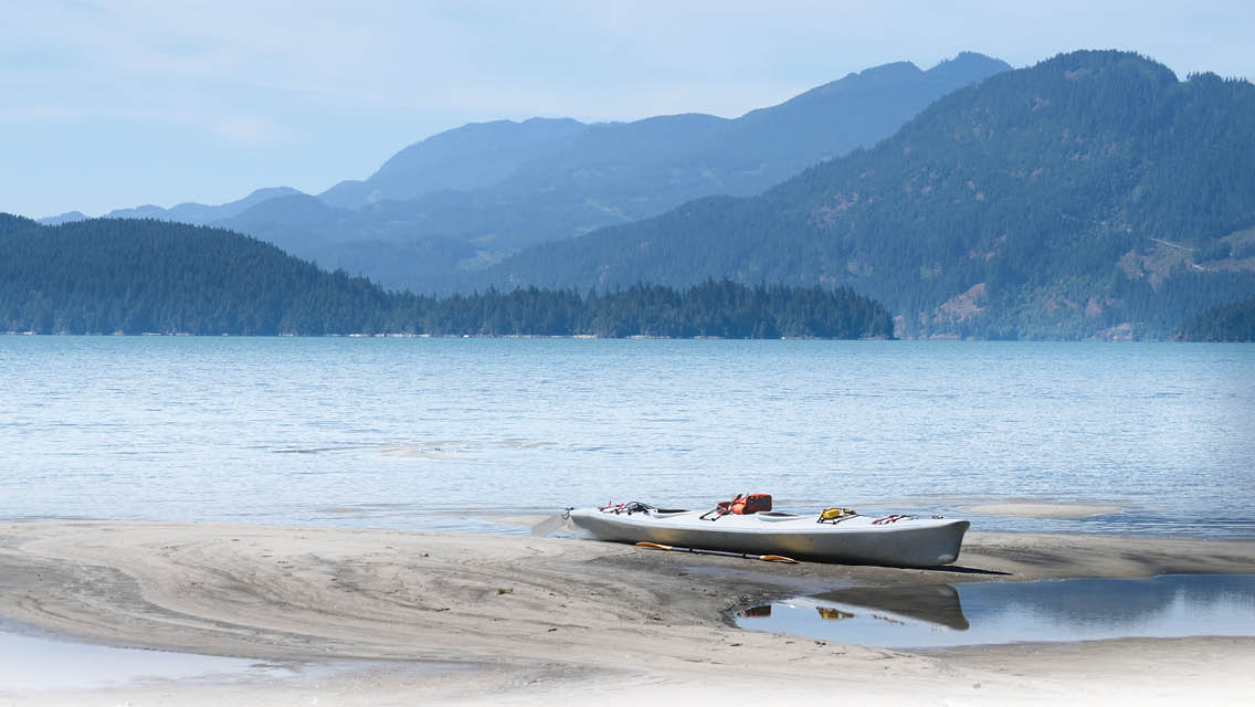 a loan canoe sits on a low level of sand on a retreating lake