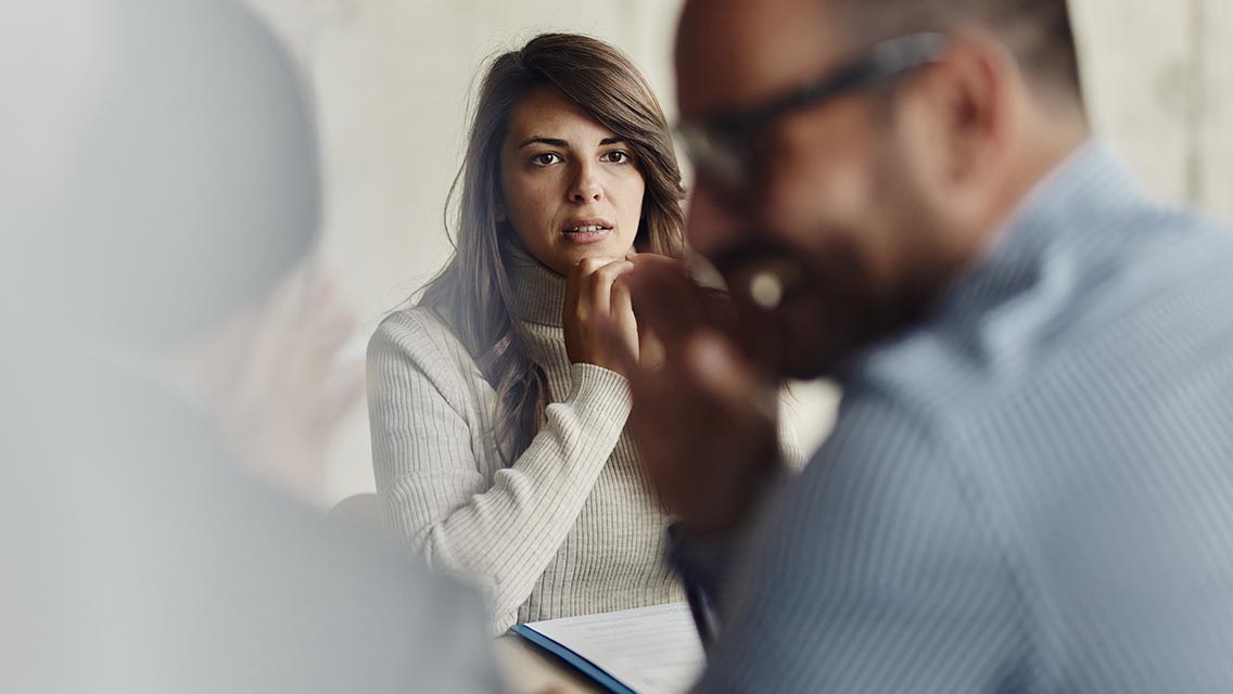 a woman looks concerned as two coworkers talk together