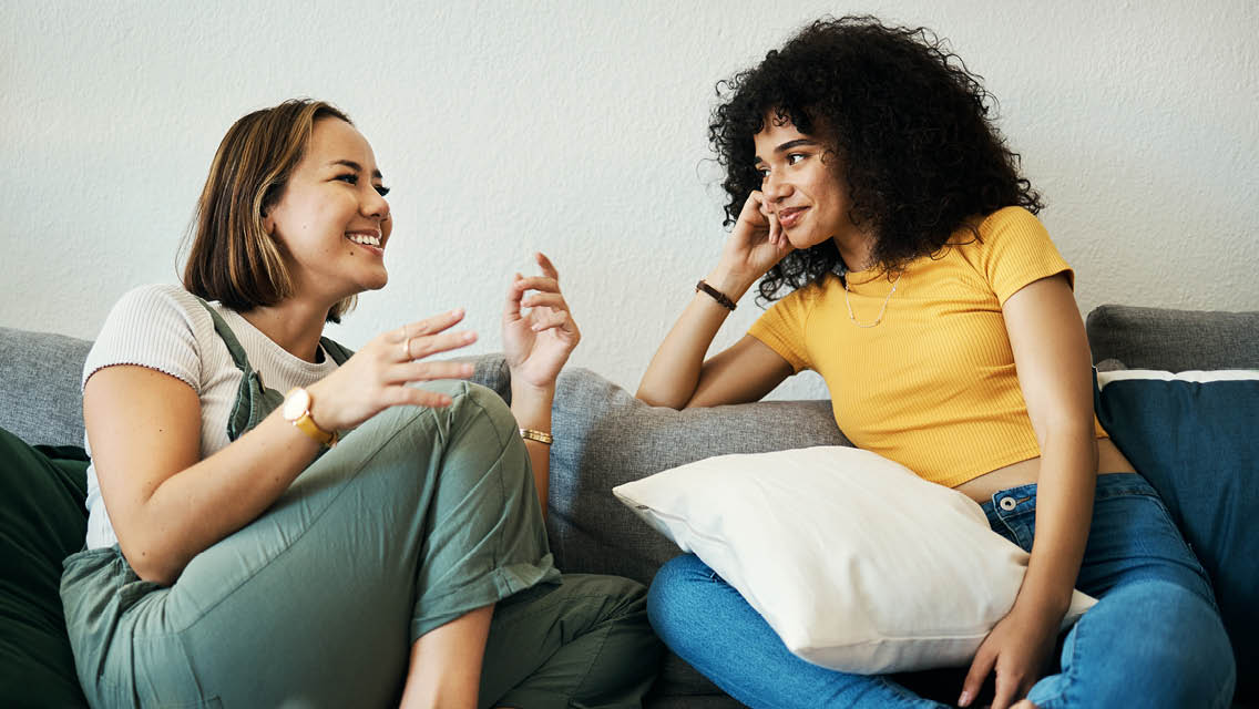 women sit chatting on a couch