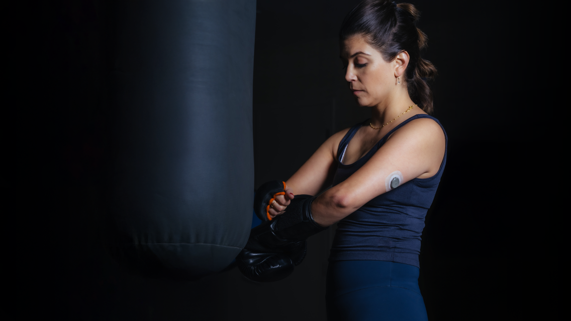 a woman prepares to workout while wearing a continuous glucose monitor